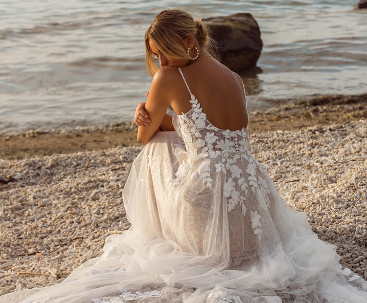 Frau trägt Hochzeitskleid mit schönem Rückenausschnitt und floraler Spitze.